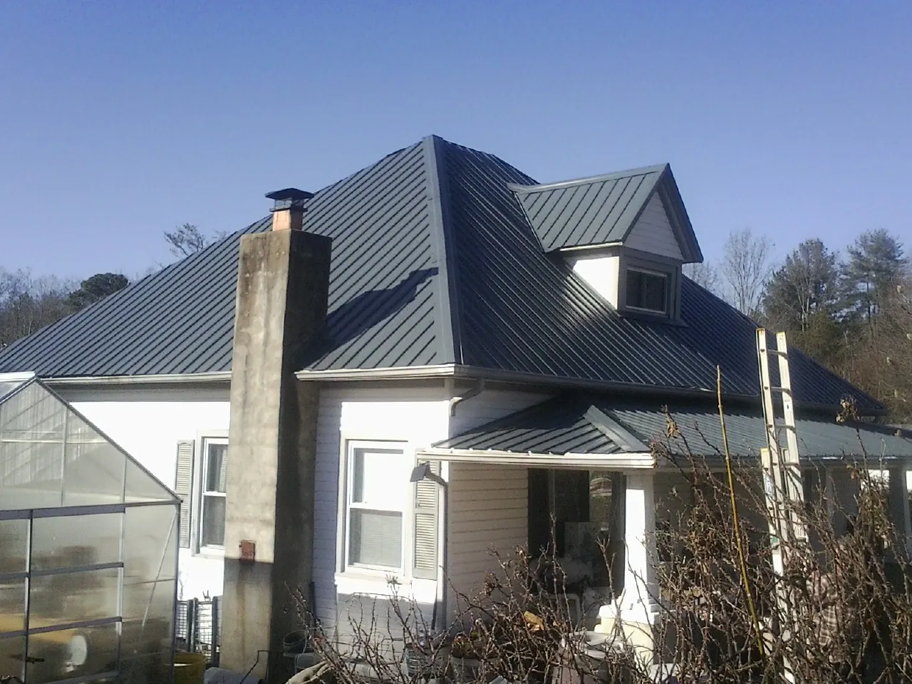 Dark blue standing seam metal roof on a white farmhouse with dormer — Slate & Tile Roof Repair by Roofing Brothers in Agate