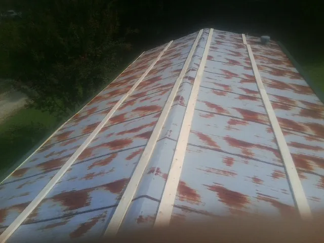 Rusted metal roof panels with new wood purlins before replacement — Storm Damage Roof Repair in Agate by Roofing Brothers