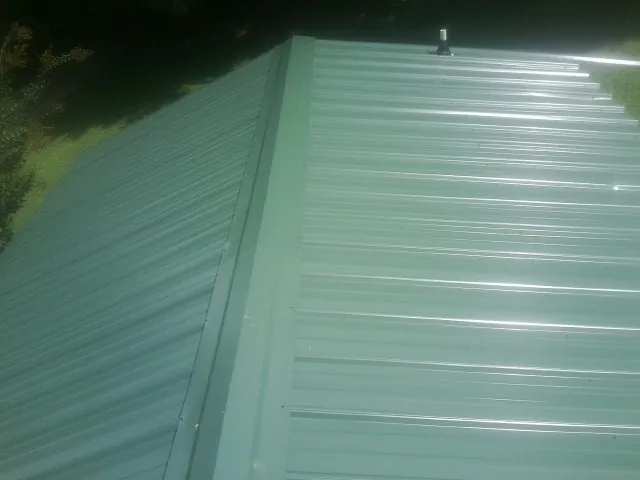 New green metal panels meeting at the ridge of a roof — Flat Roof Repair work by our crew in Agate