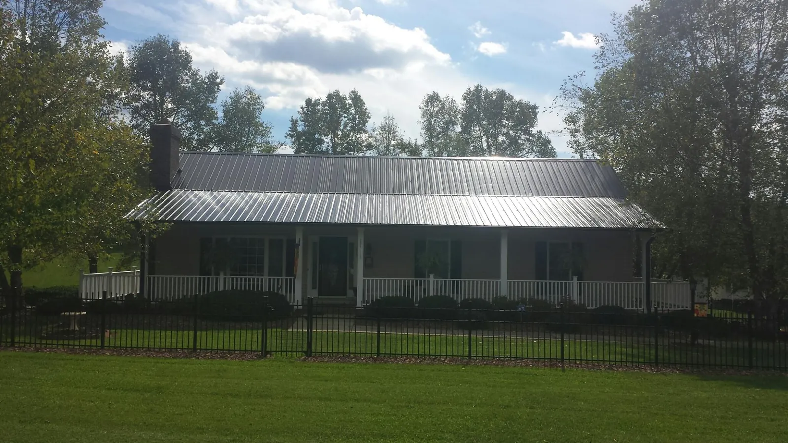 Gray metal roof on a brick ranch with a full width front porch — Gutter Guard Installation work by our crew in Agate