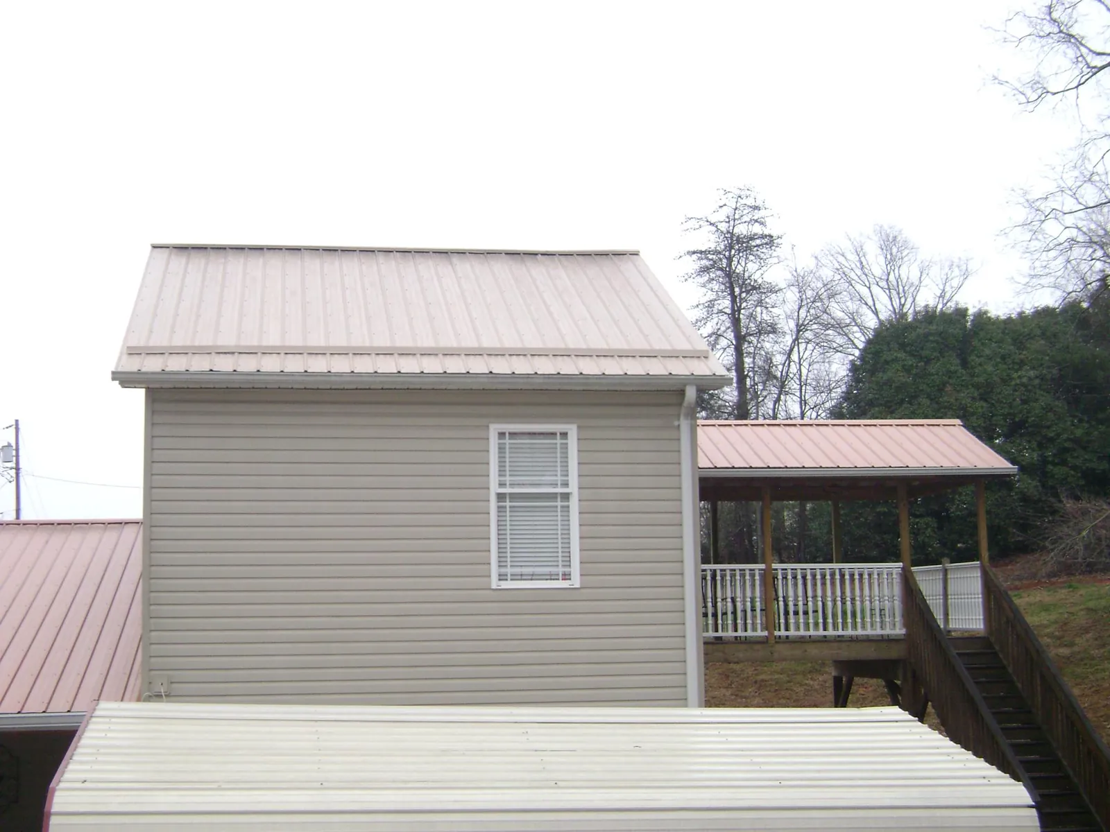 Tan metal roofs on a two story addition and attached porch, from a Roof Replacement job in Agate